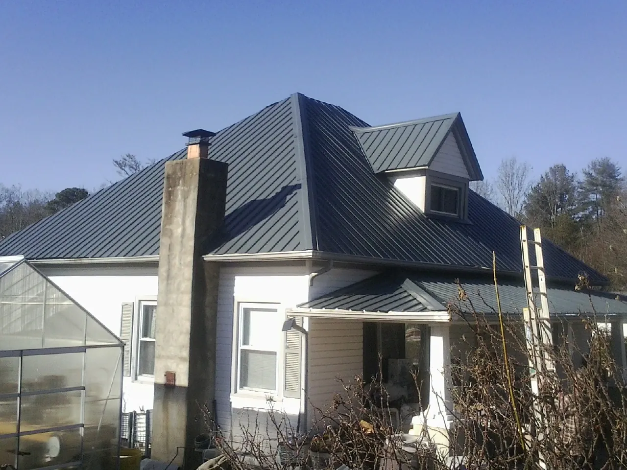 Dark blue standing seam metal roof on a white farmhouse with dormer — Slate & Tile Roof Repair by Roofing Brothers in Ardsley On Hudson