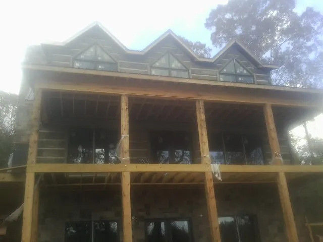 Dormers and porch framing on a large log home under construction — Roof Coating work by our crew in Ardsley On Hudson