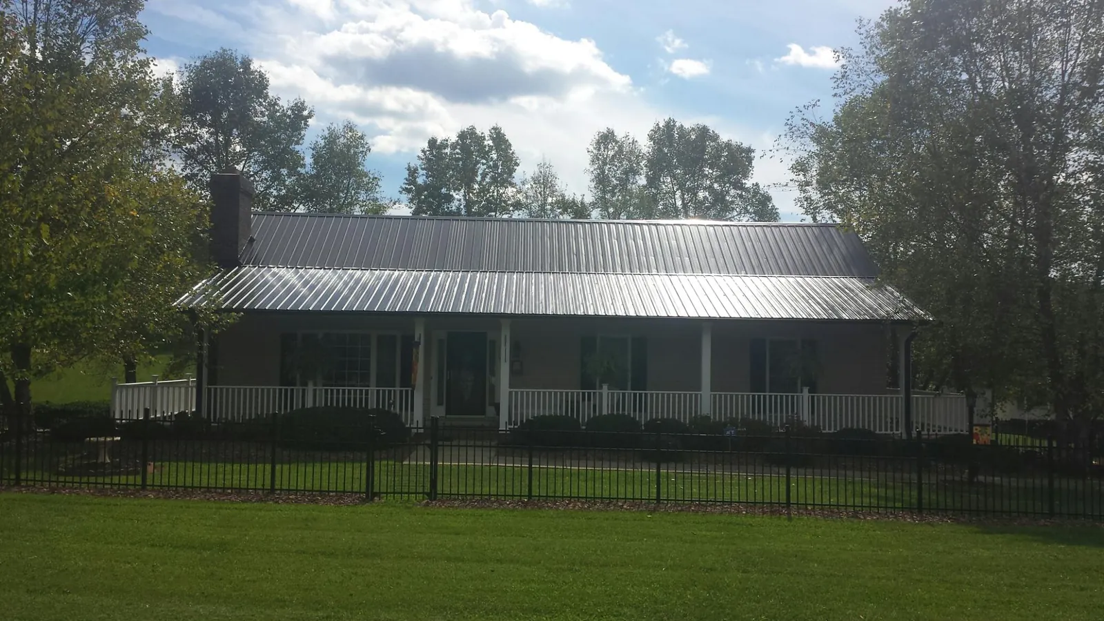 Gray metal roof on a brick ranch with a full width front porch — Gutter Guard Installation work by our crew in Ardsley On Hudson