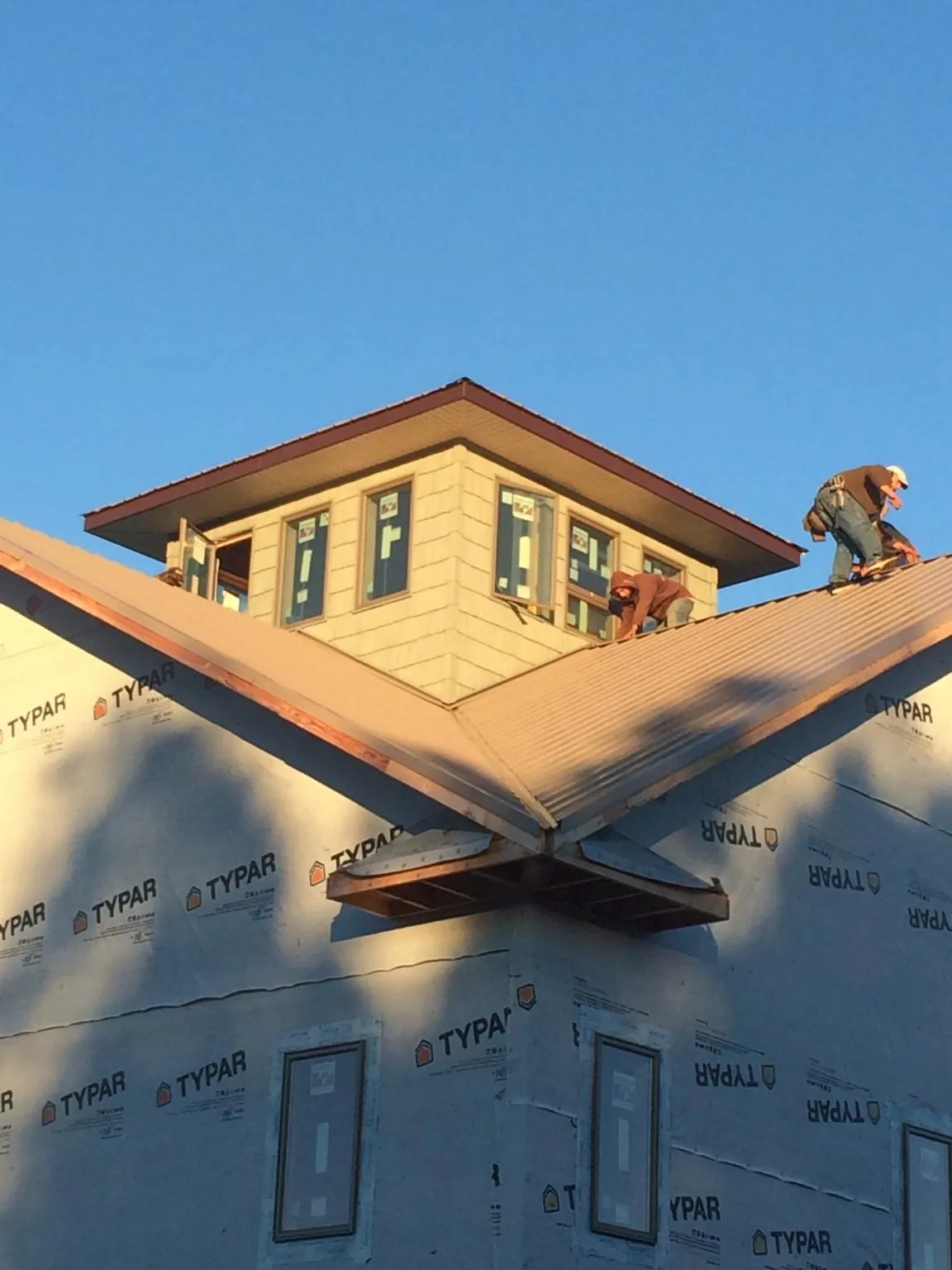 Roofers working around a rooftop cupola on a new metal roof at sunset — Roof Waterproofing in Ardsley On Hudson by Roofing Brothers
